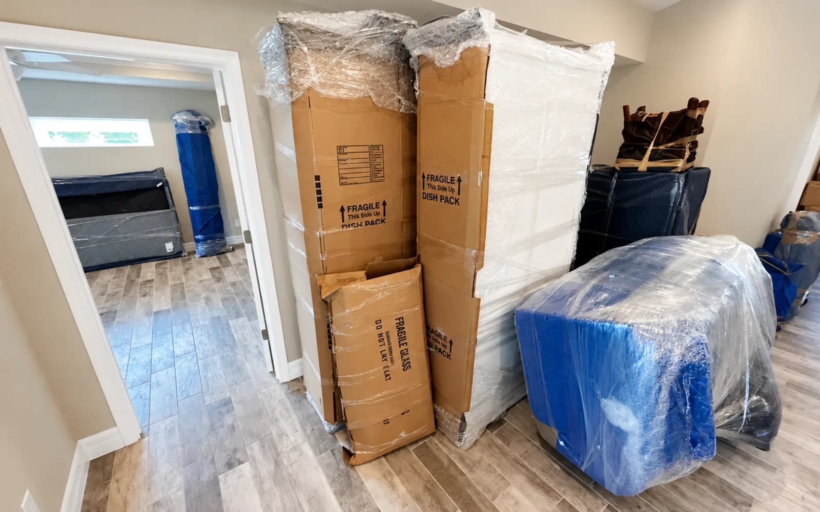 Wrapped furniture and cartons arranged in a bright residential interior