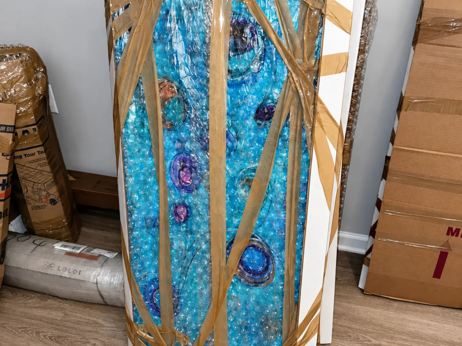 A framed painting bubble-wrapped and braced with boards for shipping