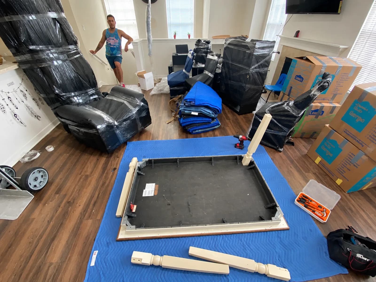 A bright room with wrapped furniture and moving supplies arranged during a residential move